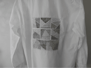 Photo d'une chemise blanche de dos avec broderie géographique apposée en technique upcycling